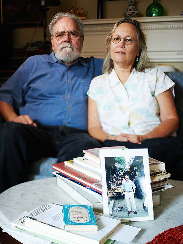 a man and a woman sitting behind a photograph of a young man